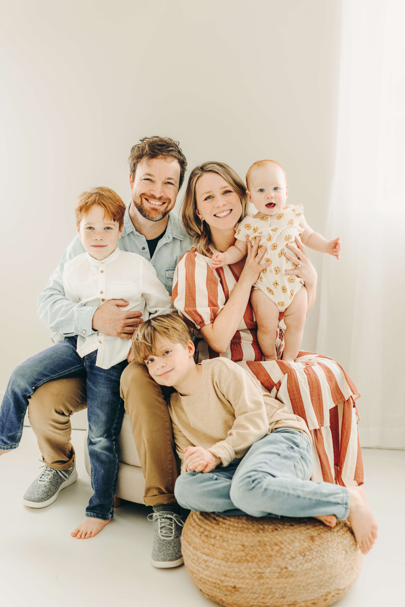 A family of five snuggles together and smiles for a picture at a photography studio in Jackson Missouri