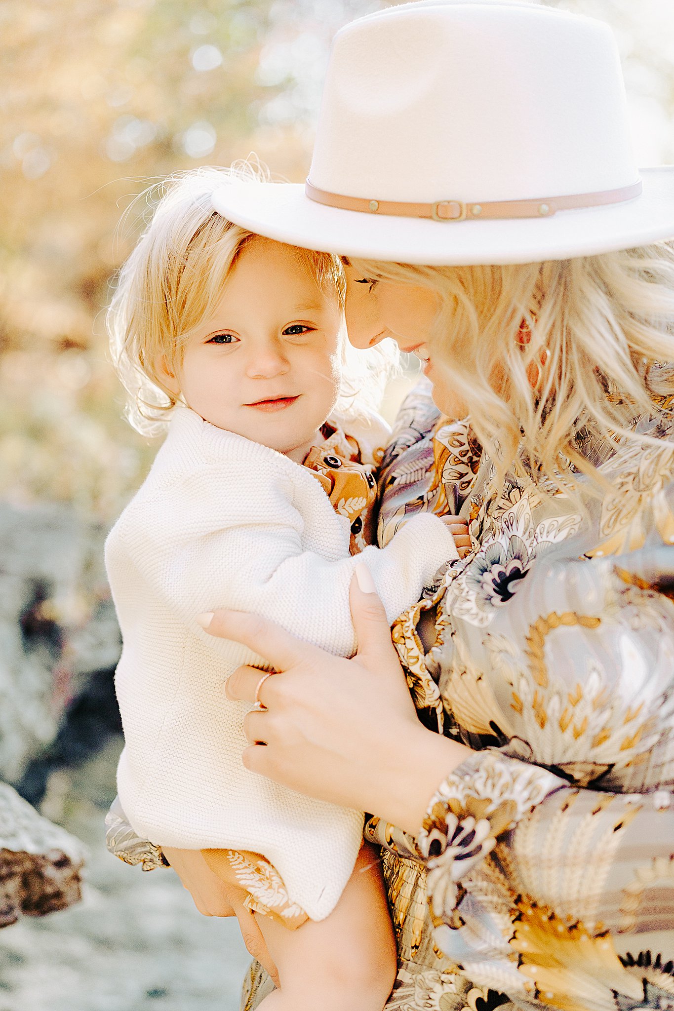 A mother in a large white hat snuggles her young daughter while holding her in a park in fall cape girardeau pediatricians